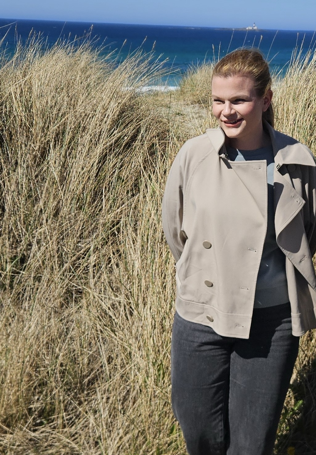 Therese, grunnlegger av Hjem med oss, i lys jakke ved havet